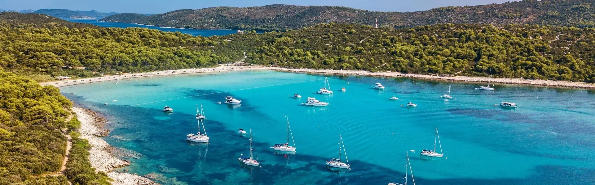 Sandbucht mit Booten und umgebendem Wald